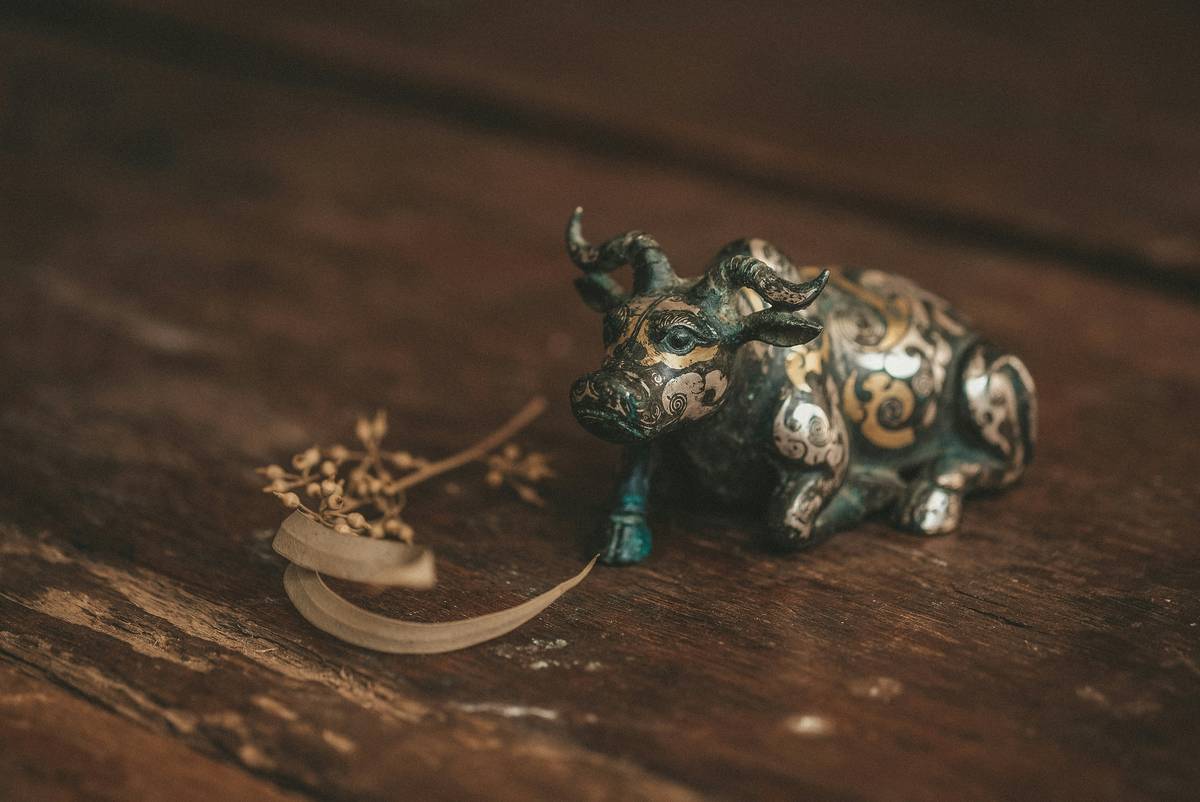 Close-up of buffalo figurines home decor on minimalist desk with open journal and brass lamp