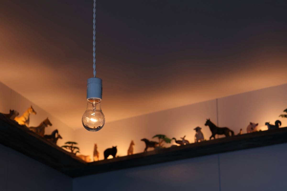 Minimalist lighted figurines home decor on a floating shelf casting artistic shadows on a white wall