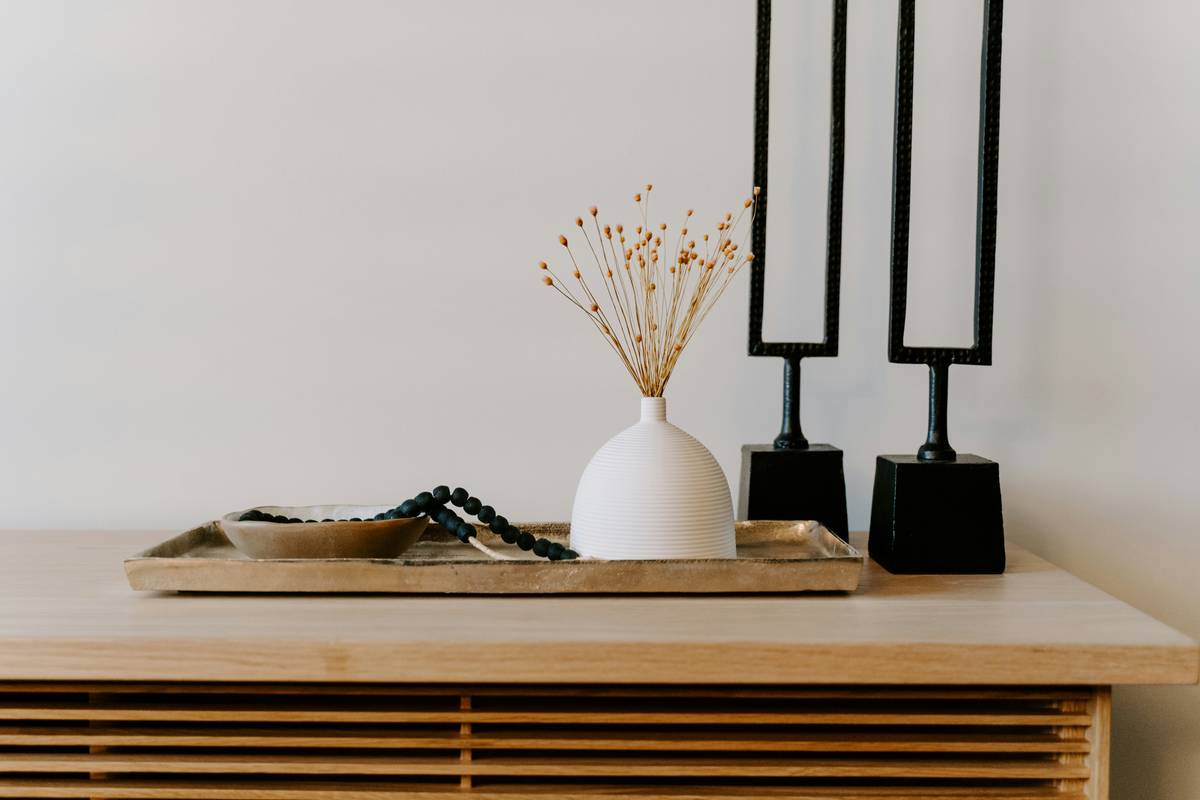 A curated shelf featuring elephant figurines home decor in ceramic and brass, arranged beside books and a small plant